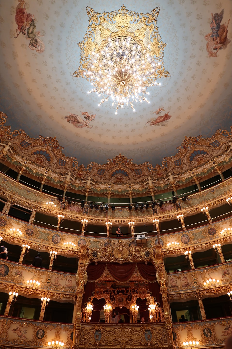 Verzierte Opernbalkone um einen großen goldenen Kronleuchter.
