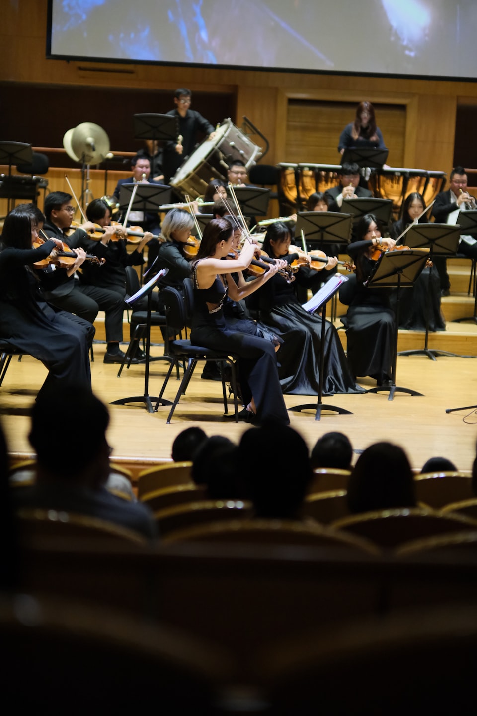 Orchester spielt klassische Musik auf einer hell erleuchteten Konzertsaalbühne.