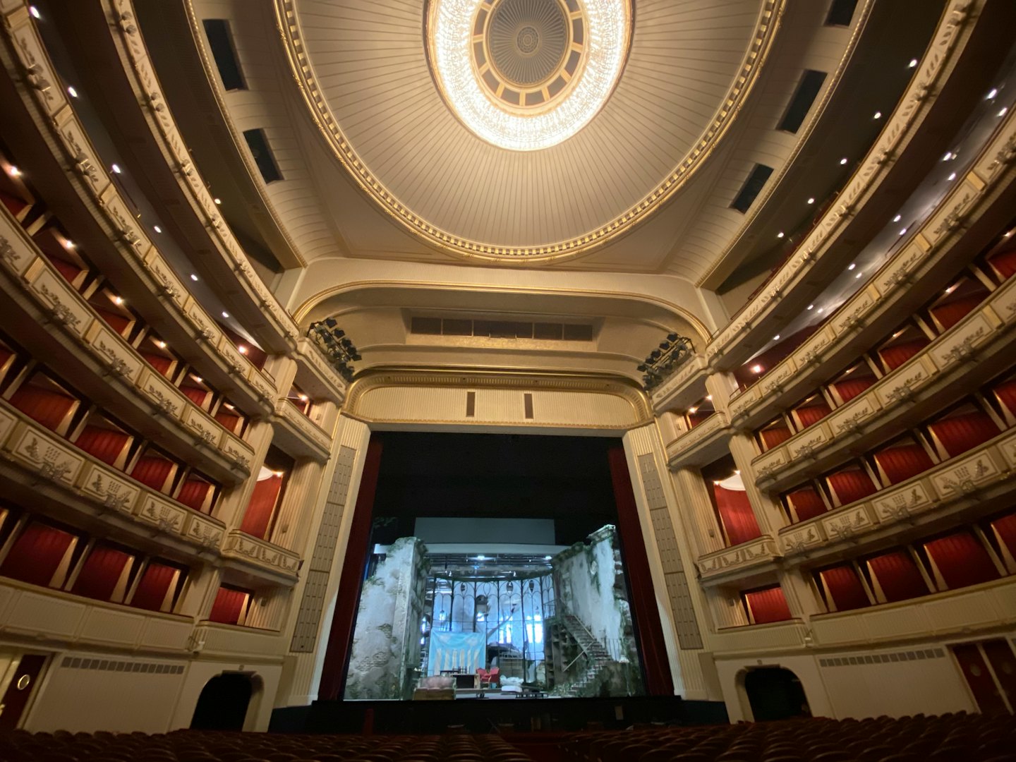 Verzierte Balkonränge eines Opernhauses mit Blick auf eine detailreiche Theaterbühne.